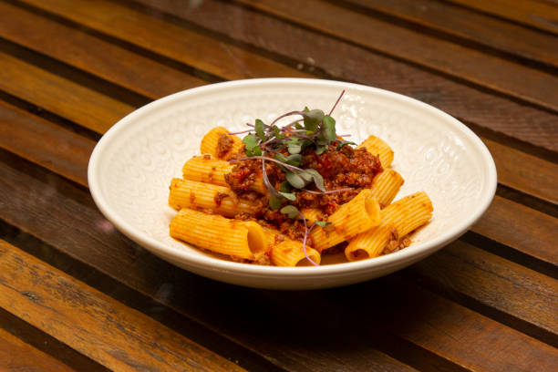 Rigatoni pasta with sugo sauce and lamb ragout, with coriander leaves on top. stock photo