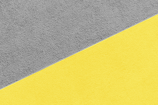 Two-tone, diagonally divided plastered wall. Photo illustrating the interaction of two color trends for 2021: 17-5104 Ultimate Gray and 13-0647 Illuminating.