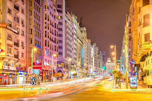 Stock photograph of cars driving on Gran Via, a main shopping street, in downtown Madrid, Spain at night.