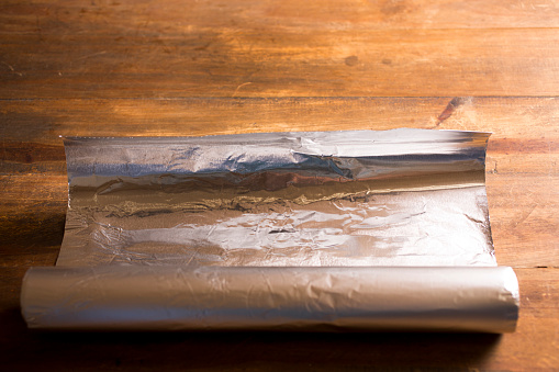 Shiny Aluminum foil on wooded table.