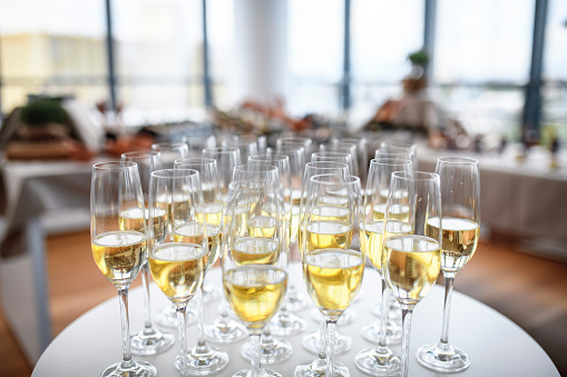 Close-up of flutes filled with sparkling wine in preparation for celebratory toasts at new business launch party.