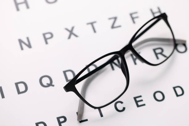 istock Glasses for vision in black frames lying on test chart closeup 1294959417