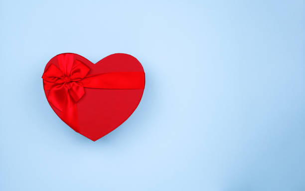 istock Red big heart-shaped gift with bow for Valentine's Day on a blue background 1294959658