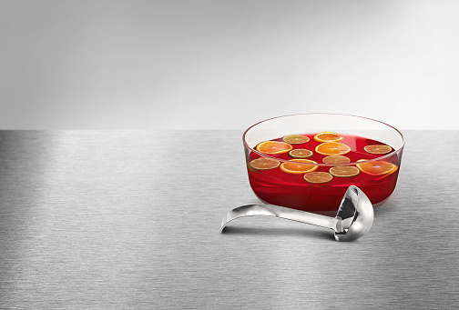 Red fruit punch bowl with oranges & lemons and a ladle on the side