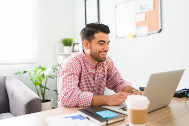 istock Smiling guy at the office is typing on his laptop 1294962920