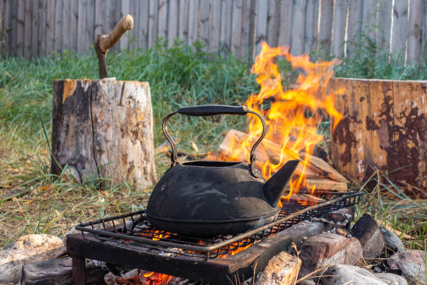 istock Hot water kettle over fire. Antique kettle on stones on a grate over a fire in the courtyard of a country house. 1294967497