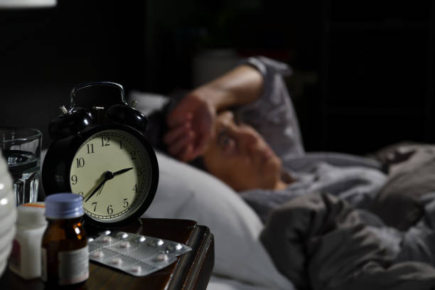 istock A depressed senior woman lying in bed cannot sleep from insomnia. Selective focus on an alarm clock 1294970388