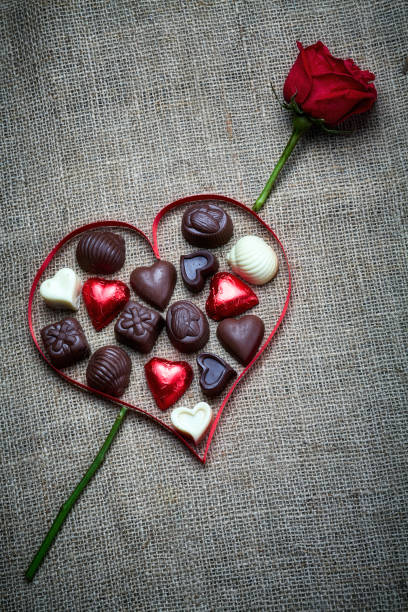 istock Valentine's Day theme: Chocolate candies in heart shape on a rustic table with a red rose 1294972589