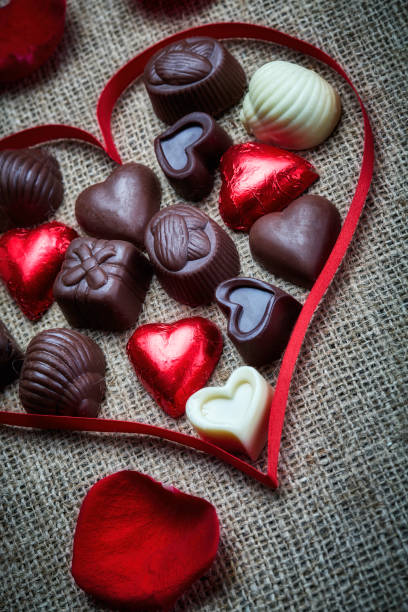 valentine's day theme: chocolate candies in heart shape on a rustic table - valentines day candy chocolate candy heart shape imagens e fotografias de stock