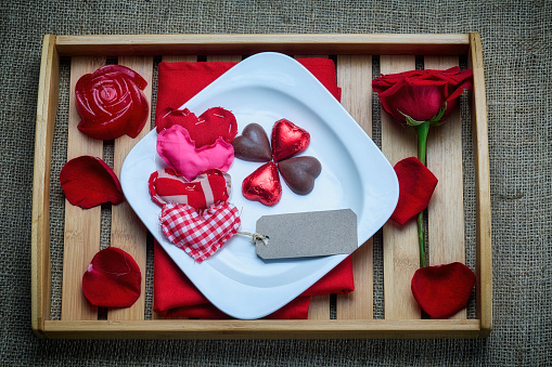 Valentine's Day theme: Red roses with chocolate candies in a plate on a tray
