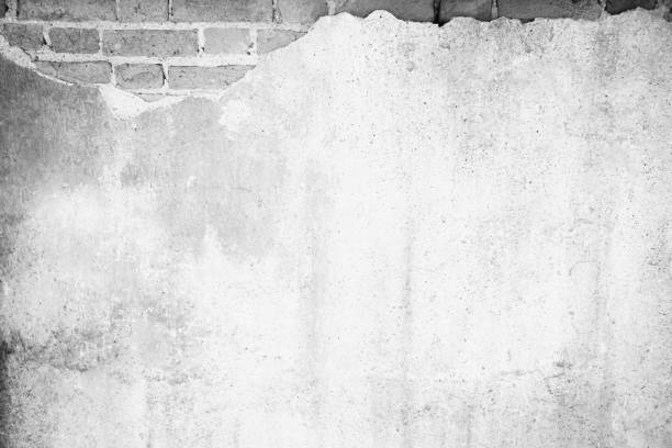 istock Black and white background concept, Old white masonry is cracking and decaying. The abstract white interior of an old broken brick wall for background, Shabby Building Facade With Damaged Plaster. 1294980094