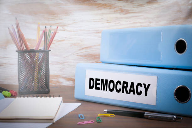istock Democracy concept. On the table Office Binder, colored pencils, pen andnotebook paper 1294980742