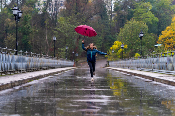 istock Woman with red umbrella having fun in rainy day 1294982645