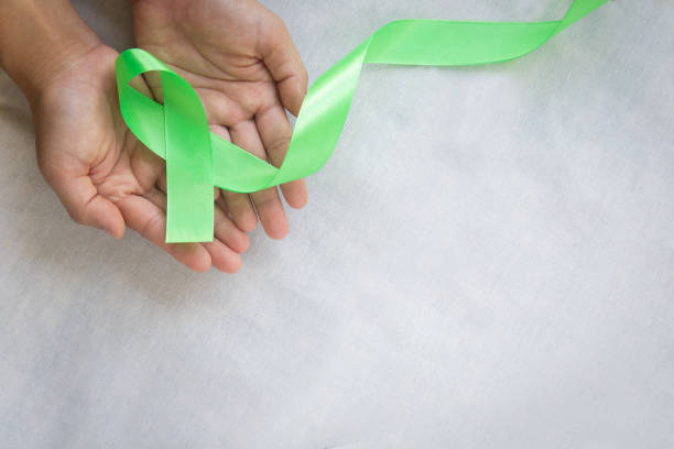 istock Hands holding emerald green or jade green ribbon on white fabric background with copy space, symbol for Liver Cancer awareness, World Cancer Day. Healthcare or hospital and insurance concept. 1294985953