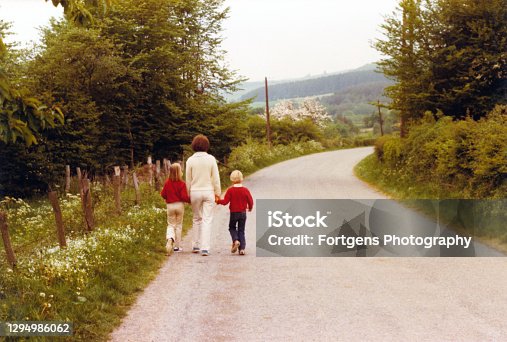 istock Vintage retro young mother walking with her son and daughter. 1294986062