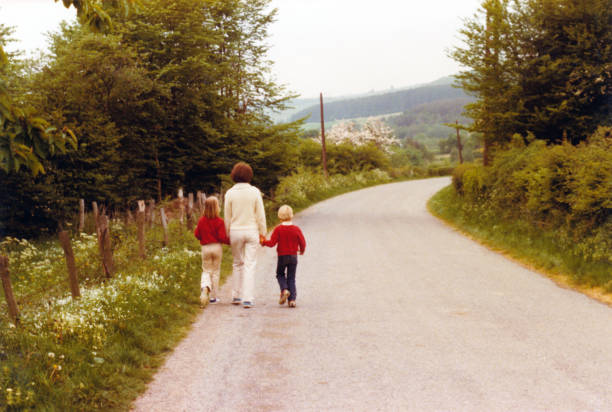 Vintage retro young mother walking with her son and daughter. Vintage 1979 image of a young mother walking hand in hand on the side of the road with her daughter and son. belgium photos stock pictures, royalty-free photos & images