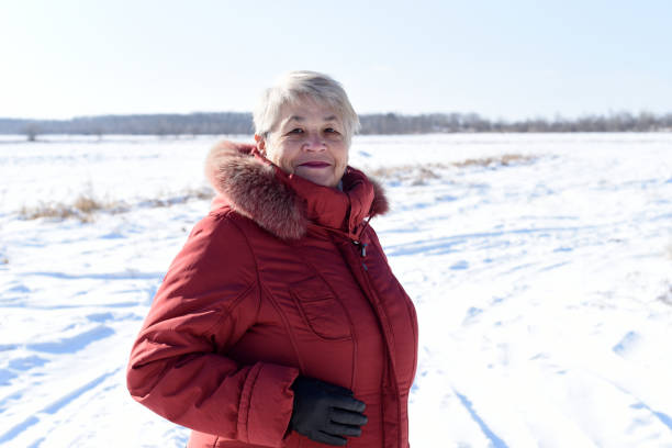 ritratto di donna anziana russa sinceramente sorridente e guardando la telecamera contro il campo innevato. inverno - russian ethnicity cold relaxation nature foto e immagini stock