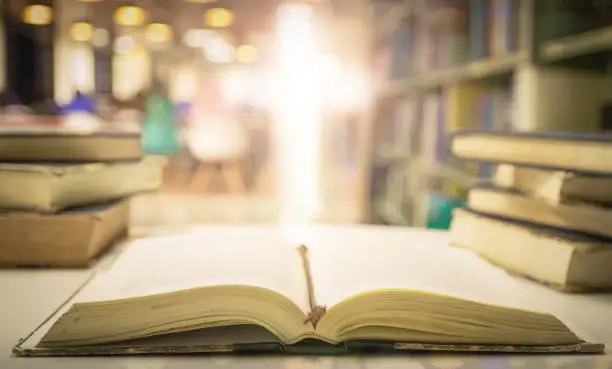 Photo of Opening book of Holy Bible with text on blurred cross background