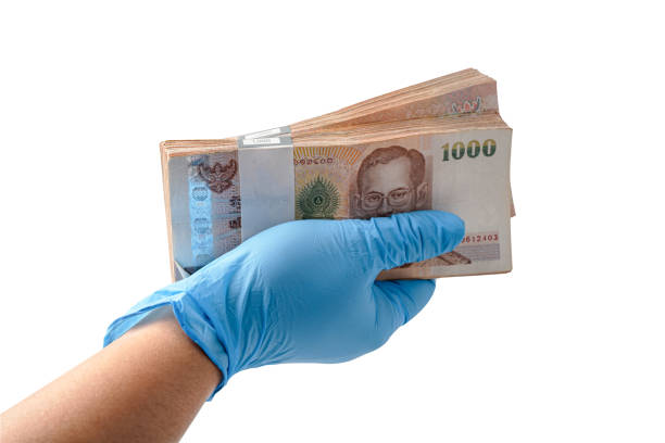 istock Hand with globe holding Thai baht banknotes isolated on white background with clipping path. 1294991006