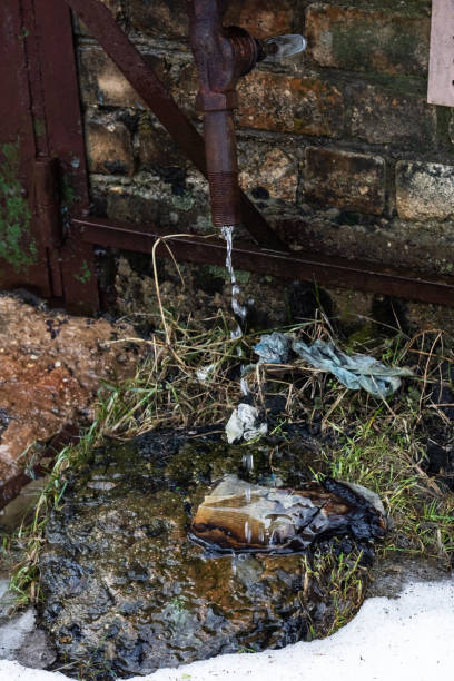 istock Drops from the pipe on a puddle, grass and snow 1294991837