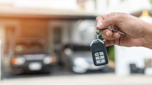 Car valet parking service enterprise, car rental, or automobile insurance business concept with owner or person handling vehicle remote key on blur parking garage background servicio de servicio de aparcacoches empresarial, alquiler de coches o concepto de negocio de seguros de automóviles con el propietario o la persona que maneja la llave remota del vehículo en el fondo del garaje de estacionamiento de desenfoque