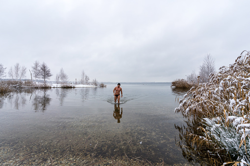 A man goes into a lake in winter for ice swimming