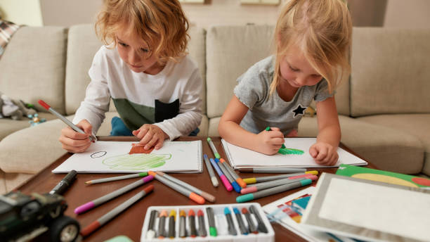 istock Focused little siblings, boy and girl drawing on paper using marker pen while spending time together at home 1294998163