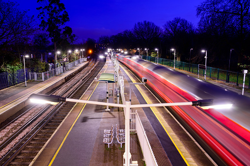 High angle view with long exposure blurred motion of commuter train on the move through Wandsworth station.