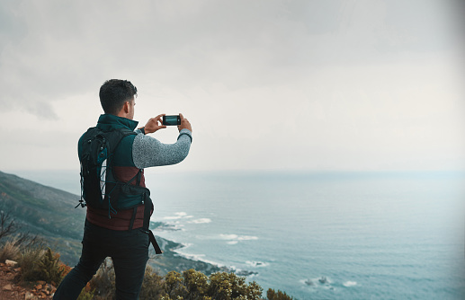 Shot of a young man taking photos while out on a hike