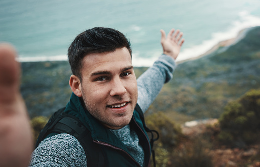 Shot of a young man taking selfies while out on a hike
