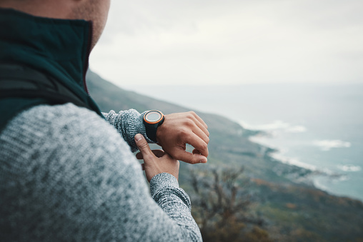 Closeup shot of an unrecognisable man checking the time while out on a hike