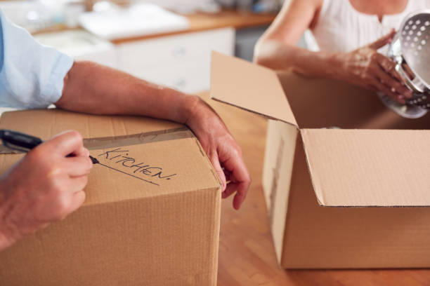 Close Up Of Senior Couple Downsizing In Retirement Boxes Ready For Move Into New Home Close Up Of Senior Couple Downsizing In Retirement Boxes Ready For Move Into New Home labeling stock pictures, royalty-free photos & images