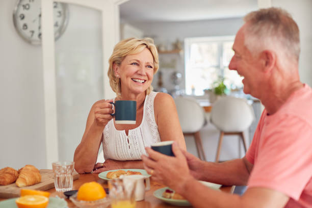 coppia in pensione a casa in cucina a fare colazione insieme - 60s senior adult breakfast cheerful foto e immagini stock