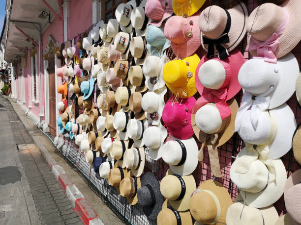 una variedad de sombreros de moda y coloridos están colgando en la pared del edificio rosa de la tienda de la acera. - selling merchandise craft thailand fotografías e imágenes de stock