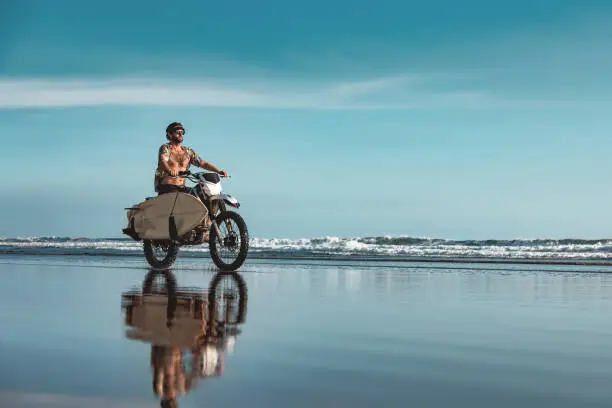 Photo of Real Bali surfer on motorcycle at ocean beach