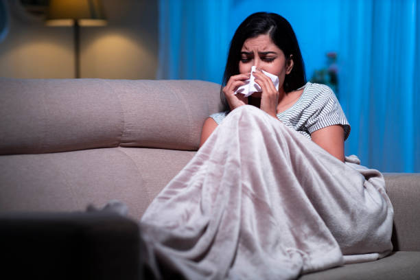 young women sick suffering from cold sitting on sofa stock photo