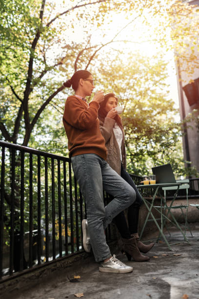 istock Two young women friends drinking coffee on the balcony 1295007866