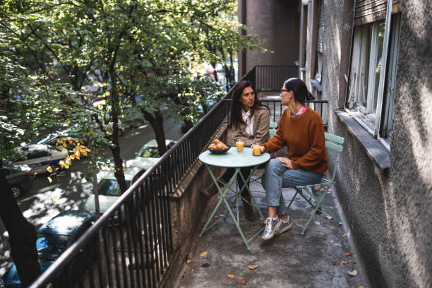 istock Two young women friends drinking coffee on the balcony 1295007906