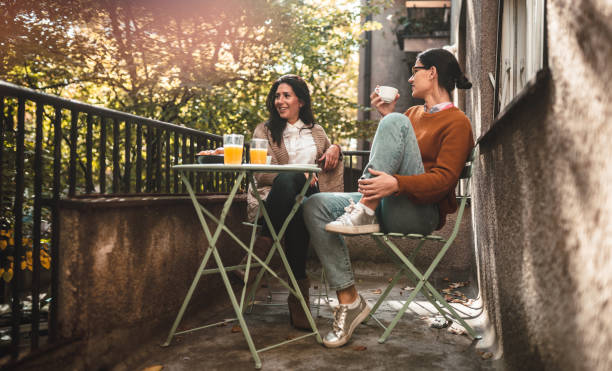 Two young women spending time together on terrace with coffee