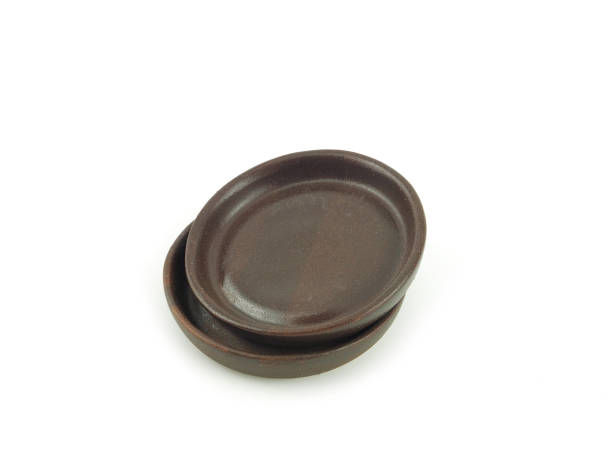 istock Empty brown old clay saucers stack, for food use home or restaurant isolated on a white background. Kitchen accessory. 1295010112