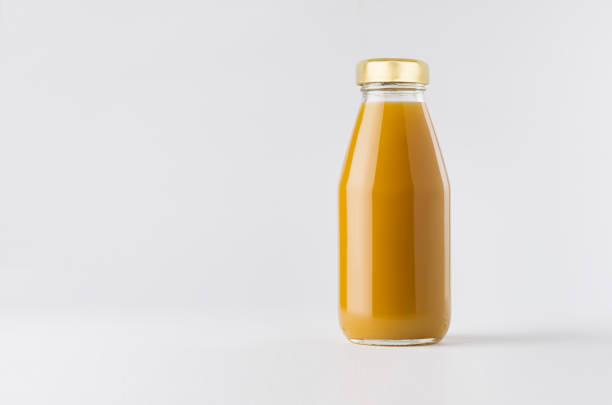 istock Orange mango juice in glass bottle with gold cap mock up on white background with copy space, template for packaging, advertising, design product, branding. 1295011418