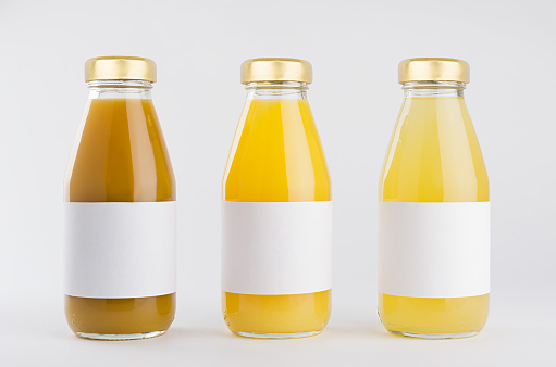 Orange, yellow fruit juices collection in glass bottles with cap, white blank labels in row mock up on white background, template for packaging, advertising, design product, branding.