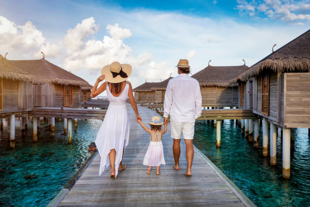 a family in white summer clothing walks over a wooden pier in the maldives - empreendimento turístico imagens e fotografias de stock