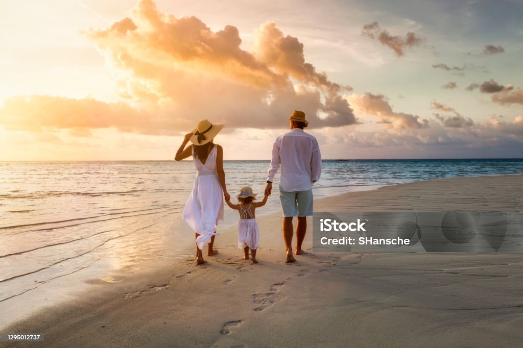 O familie merge mână în mână pe o plajă paradis tropical în timpul apusului de soare - Fotografie de stoc Familie fără redevențe O familie merge mână în mână pe o plajă paradis tropical în timpul apusului de soare - Fotografie de stoc Familie fără redevențe