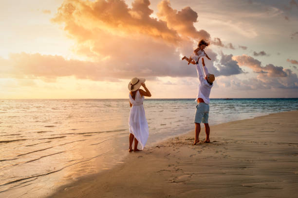 A happy family is having fun on a tropical beach during sunset A happy family in white summer clothing is having fun on a tropical beach during sunset time  life in Maldives stock pictures, royalty-free photos & images