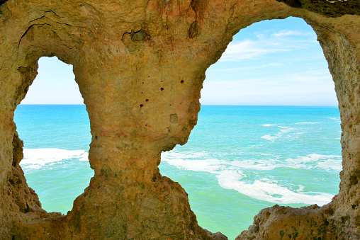 Algar Seco, Carvoeiro, Lagoa, Algarve / Faro district, Portugal: view over the Atlantic ocean through the rock windows at the 'Boneca' rock formation, the are known as the 'eyes of the dolll' (boneca).