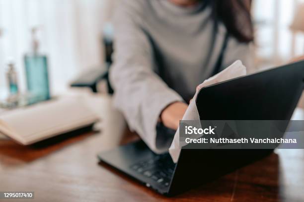 A Working Woman Wipe The Laptop Clean In Home Officework From Home And Covid19 Concept Stock Photo - Download Image Now
