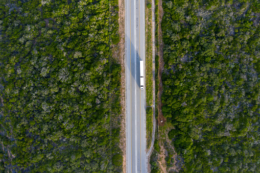 Top down view of a large transport tuck travelling down a national road in South Africa. The road is surrounded by lush green vegetation