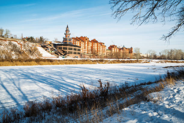 Winter view of the city from the opposite bank of the frozen river stock photo