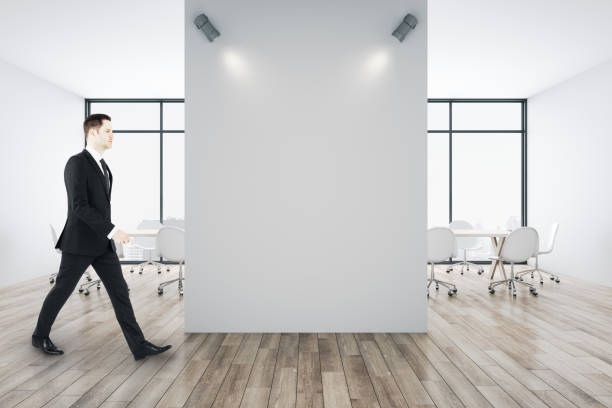istock Businessman walking in in conference room with blank white wall. 1295018749